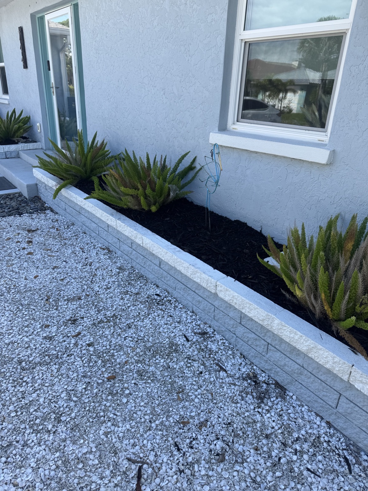 Mulch installation and bed edging service in North Port FL — dark mulch with ferns and stone borders